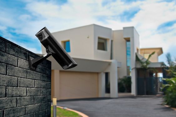 A security camera on a wall in front of a modern house